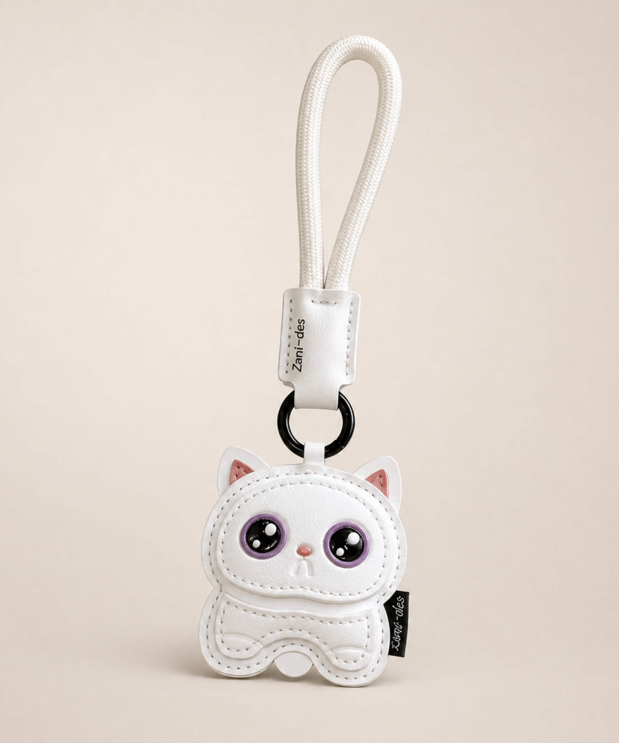 Cute Kitty PU leather keychain in white with purple eyes and wrist strap on a neutral studio background.